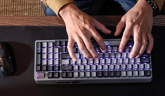 Clavier mécanique cooler master sur un bureau utilisé par une personne